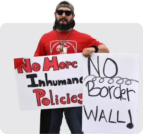 Marcher at the 20th Annual Cesar Chavez March in San Juan, Texas, holding a sign advocating for changes in immigration policies.